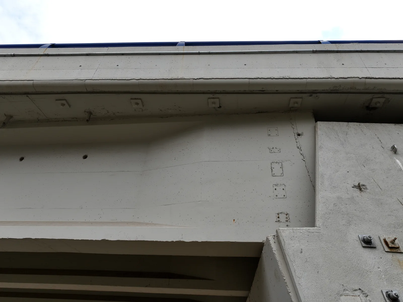 Detalle de la fascia y el alma de una viga de puente: fisura vertical, regueros de oxido y las placas de anclaje, captados desde el aire